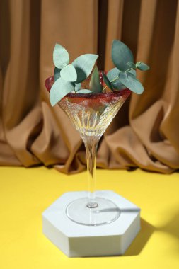 Okaliptüs yapraklı güzel martini bardakları kahverengi perdeye karşı sarı yüzeyde.