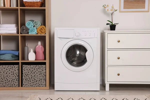 Stylish laundry room with washing machine and chest of drawers. Interior design