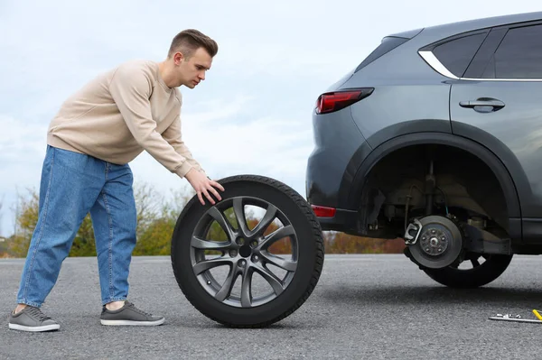 도로에서 자동차 타이어를 교체하는 젊은이 — 스톡 사진