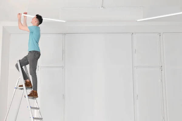 Hombre Joven Instalando Lámpara Techo Escalera Interior — Foto de Stock
