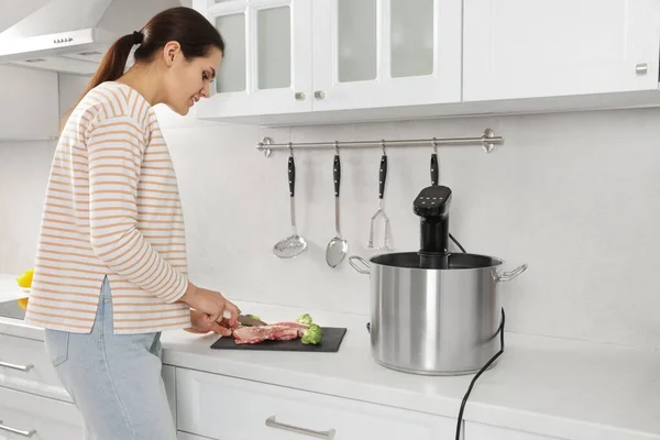 女人在厨房里用苏打水锅在锅边切肉 热浸循环系统 — 图库照片