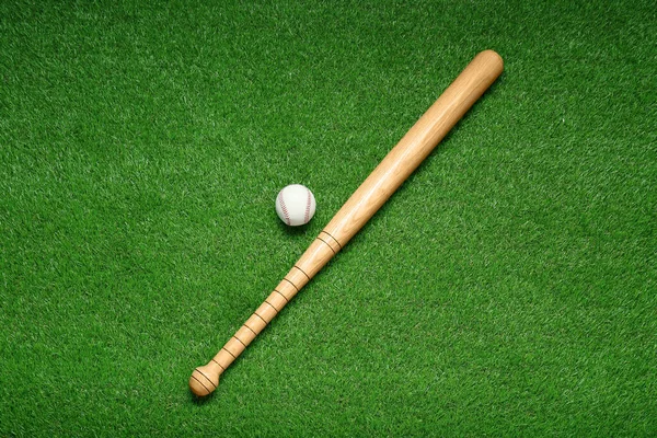 緑の芝生の上で木製の野球バットとボール フラットレイアウト スポーツ用具 — ストック写真