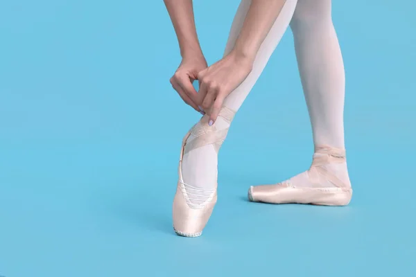 Genç Balerin Açık Mavi Arka Planda Sivri Uçlu Ayakkabılar Bağlıyor — Stok fotoğraf
