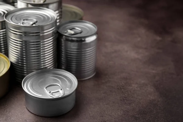 Many closed tin cans on brown table. Space for text
