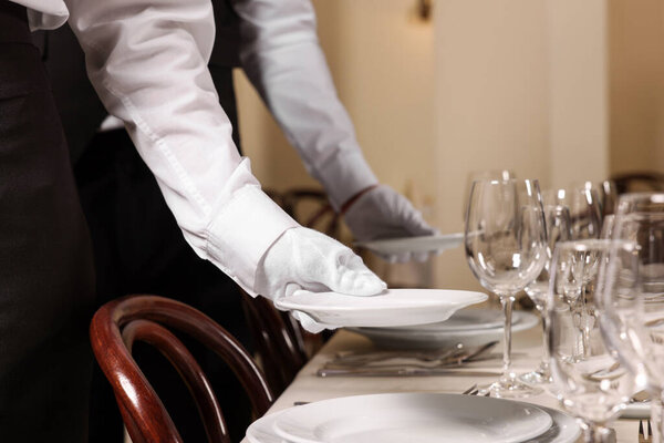 Woman setting table in restaurant, closeup. Professional butler courses