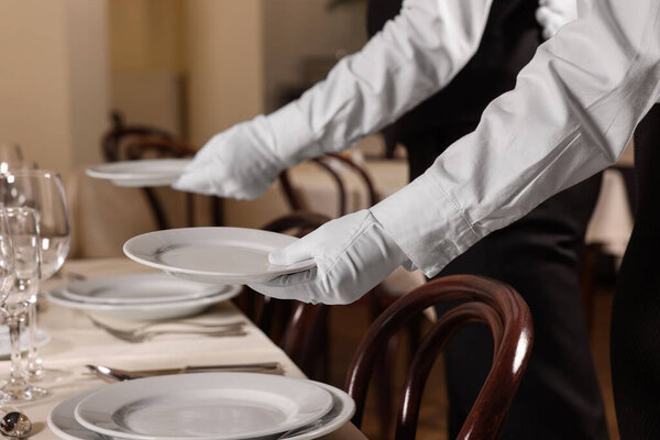 Woman setting table in restaurant, closeup. Professional butler courses