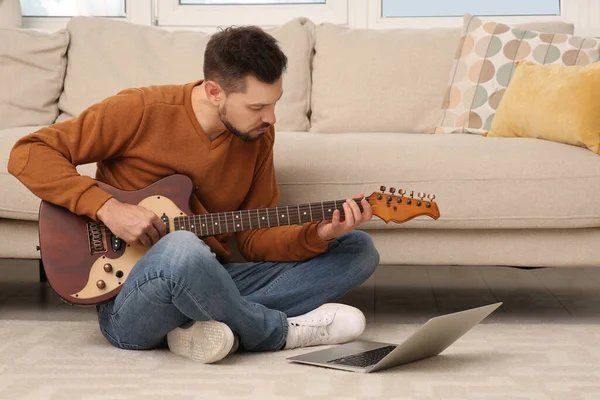 Man learning to play guitar with online music course at home. Time for hobby