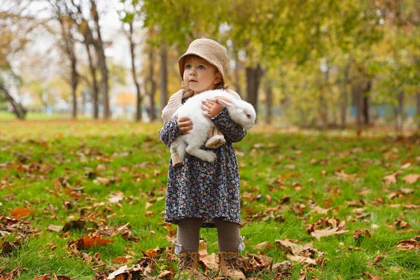 秋の公園でかわいい白いウサギと一緒に歩く女の子 — ストック写真