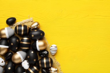 Bir sürü güzel dekore edilmiş Paskalya yumurtaları sarı ahşap masa üzerinde, düz yatıyordu. Metin için boşluk