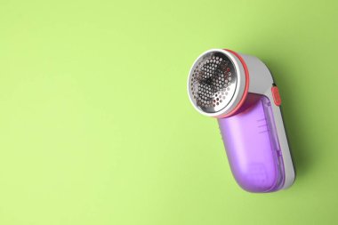 Açık yeşil arka planda modern kumaş traş makinesi, üst manzara. Metin için boşluk