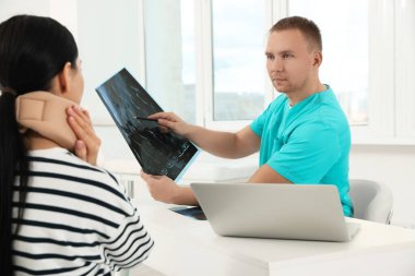 Doctor with neck MRI image consulting patient in clinic