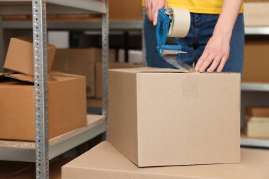 Postane çalışanı paketleme kutusu, kapalı alanda bantlı, yakın plan.