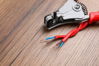 Cutters and stripped wire on wooden table, closeup. Space for text