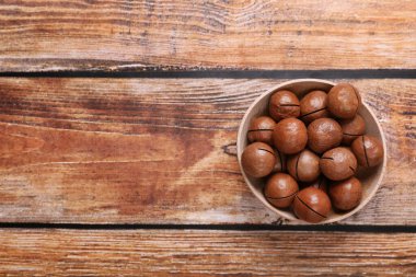 Tahta masadaki kasede bulunan lezzetli organik Macadamia fındıkları. Metin için boşluk