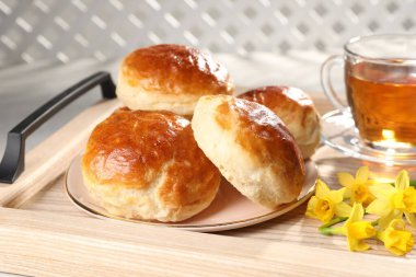 Taze pişmiş soda, bir fincan çay ve ahşap tepside nergis, yakın plan.