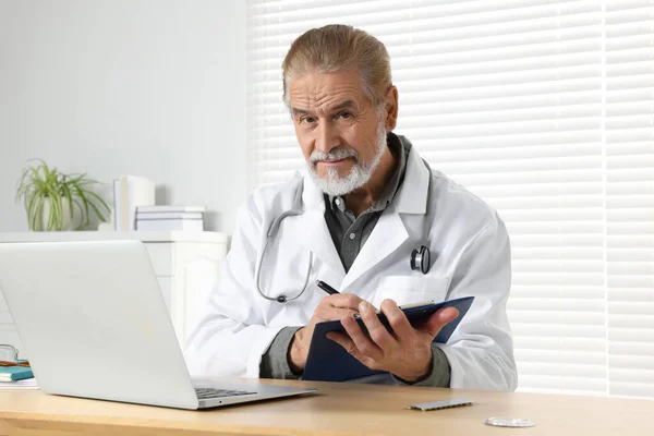 Médico Sênior Com Laptop Prancheta Consulta Paciente Mesa Madeira Clínica — Fotografia de Stock