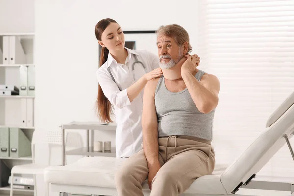 Orthopedist applying cervical collar onto patient\'s neck in clinic