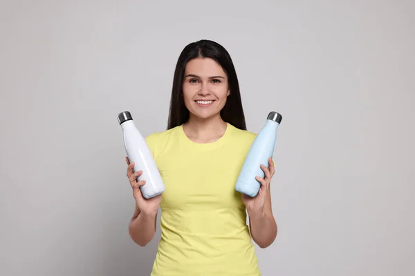 Mujer Joven Con Botellas Termo Sobre Fondo Gris Claro —  Fotos de Stock