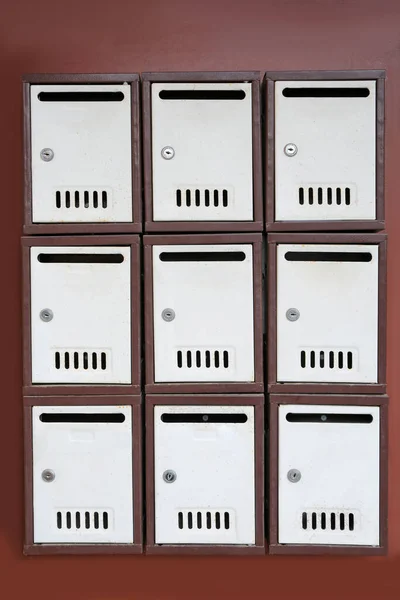 Many metal letter boxes on brown wall