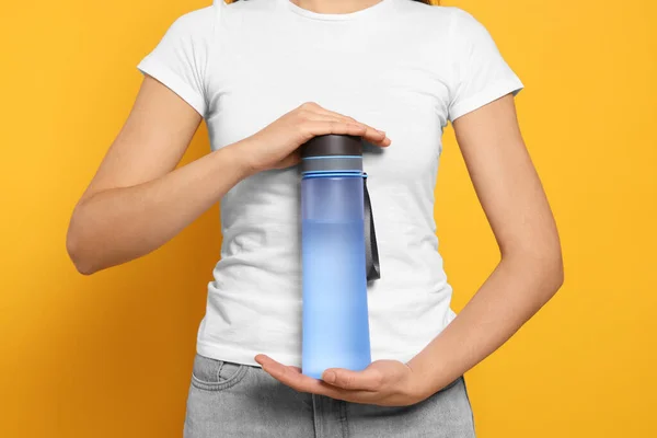 Woman Holding Bottle Water Orange Background Closeup — Stockfoto