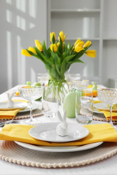 stock image Festive table setting with glasses, painted eggs and vase of tulips. Easter celebration