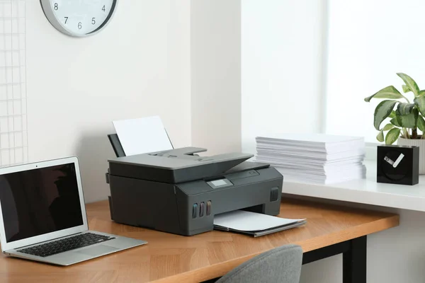 办公室的木制桌子上装有纸张和笔记本电脑的现代打印机 — 图库照片