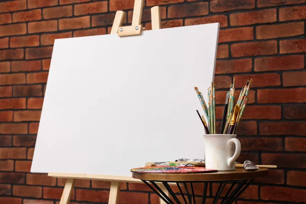 Wooden Easel Blank Canvas Different Art Supplies Brick Wall Closeup — Stock Photo, Image