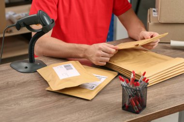 Post office worker with adhesive paper bags at counter indoors, closeup