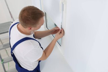 Üniformalı işçiler içeriye paten penceresi kuruyor.