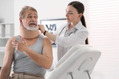 Ortopedist klinikteki hastanın boynuna boyun tasması takıyor.