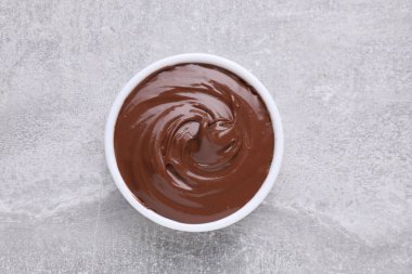 Gri desenli masa üzerinde çikolata ezmeli kase, üst görünüm.