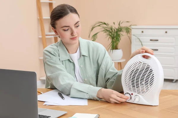 Young Woman Adjusting Temperature Modern Electric Fan Heater Wooden Table — Stock Photo, Image