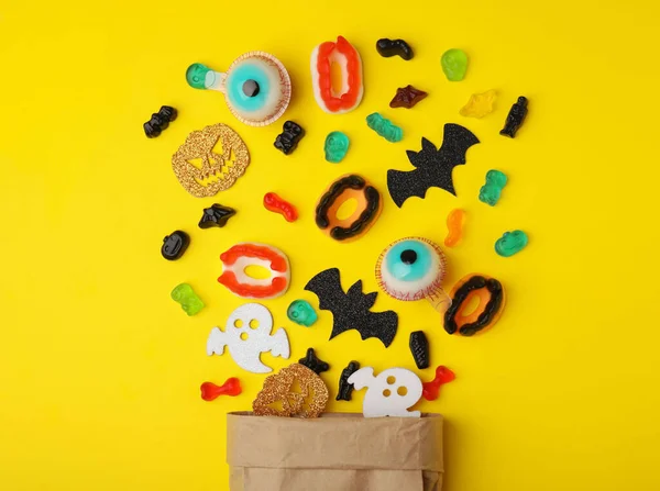 Papiertüte Mit Leckeren Bonbons Und Halloween Dekorationen Auf Gelbem Hintergrund — Stockfoto
