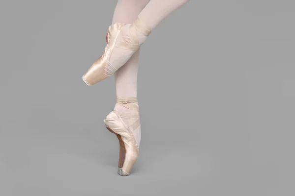 穿着尖皮鞋的年轻芭蕾舞演员在灰色背景下练习跳舞 — 图库照片