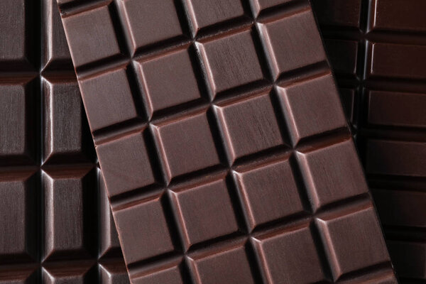 Many delicious dark chocolate bars as background, top view