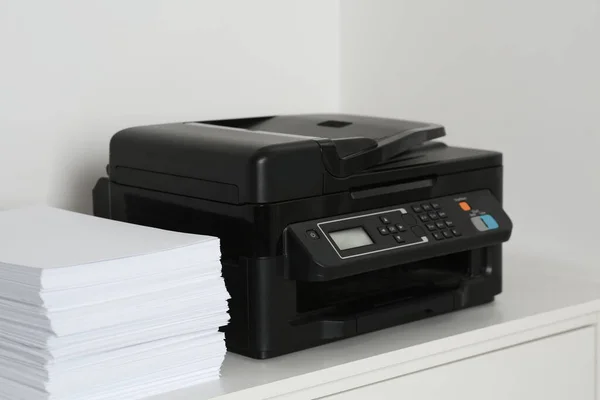 Modern printer and paper sheets on white table indoors