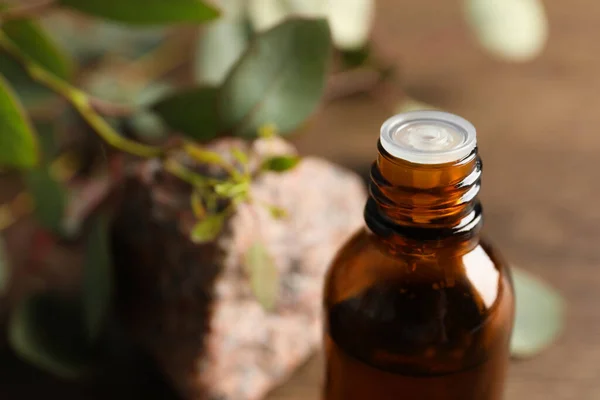 Eine Flasche Ätherisches Eukalyptusöl Stein Und Blätter Auf Einem Holztisch — Stockfoto