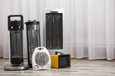 Different modern electric heaters on floor in room