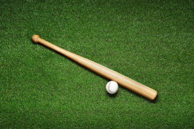 Wooden baseball bat and ball on green grass, flat lay. Sports equipment clipart