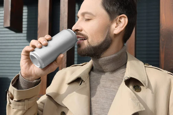 Handsome man drinking from tin can outdoors, closeup