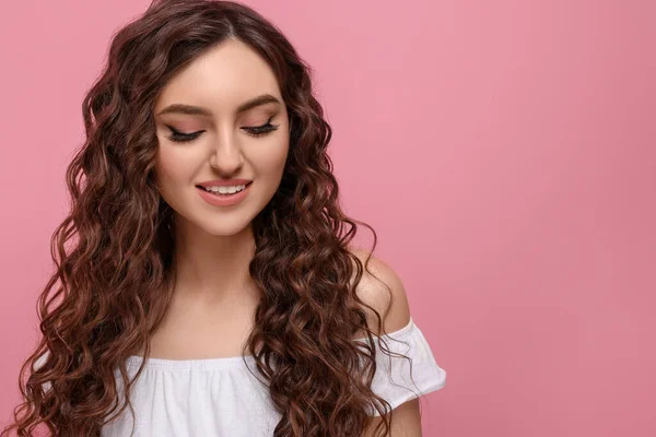 ピンクの背景に長い巻き毛の髪を持つ美しい若い女性 テキストのためのスペース — ストック写真