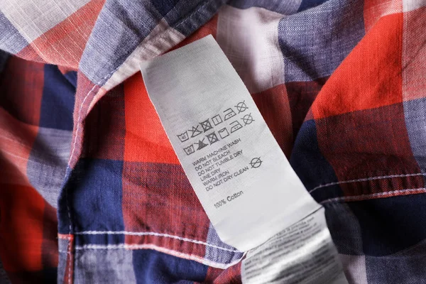 Clothing label on beautiful checkered garment, closeup