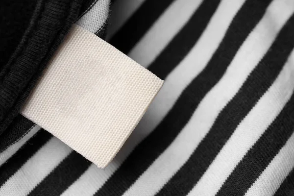 Clothing label on striped garment, top view. Space for text