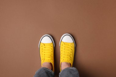 Kahverengi arka planda şık ayakkabılı bir kadın.