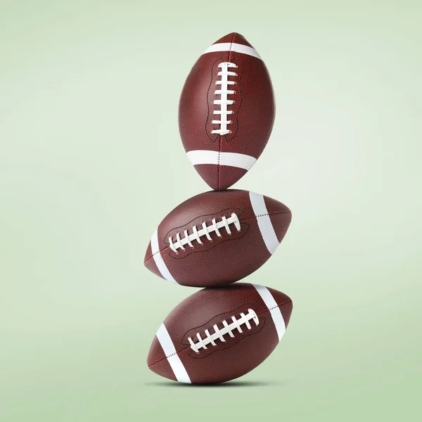 Stack of American football balls on pale light green background
