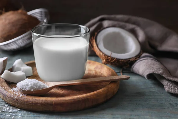 stock image Glass of delicious coconut milk, spoon with flakes and nuts on wooden table, space for text