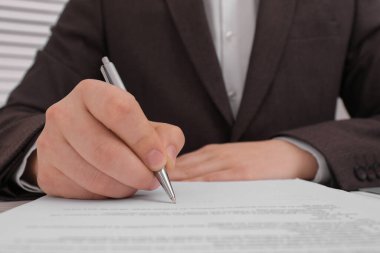 Man signing document at table, closeup view