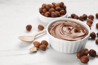 Çikolata ezmeli kase ve beyaz mermer masada fındıklar. Metin için boşluk