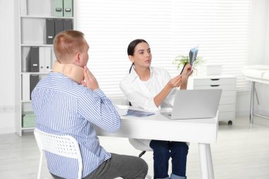 Doctor with neck MRI image consulting patient in clinic