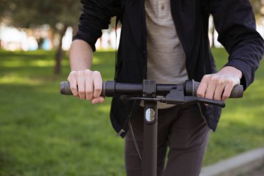 Parkta modern elektrikli scooter kullanan adam, yakın plan.